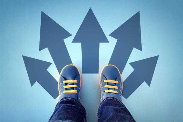 Feet standing on a surface with multiple arrows pointing in different directions, symbolizing career choices and guidance.